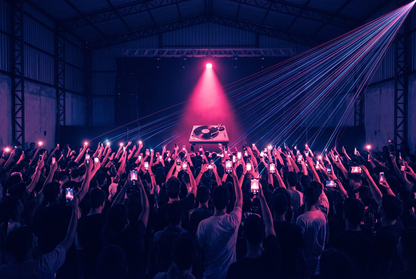 milhares de fãs jovens vistos de trás num ginásio lotado, braços e celulares erguidos para um palco onde há só um toca-discos sob um foco de luz; fios luminosos de dados sobem de cada pessoa e convergem para um ponto fora do quadro
